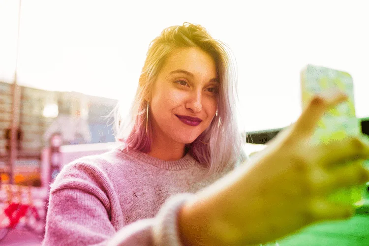 Smiling woman taking a selfie outdoors.